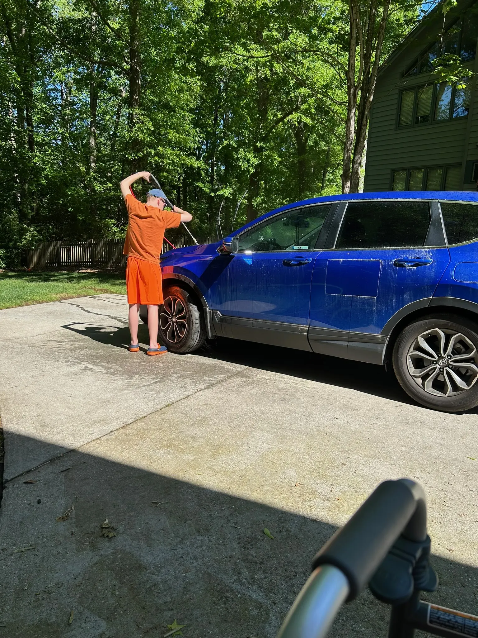 Alexander rinsing the front of a blue SUV