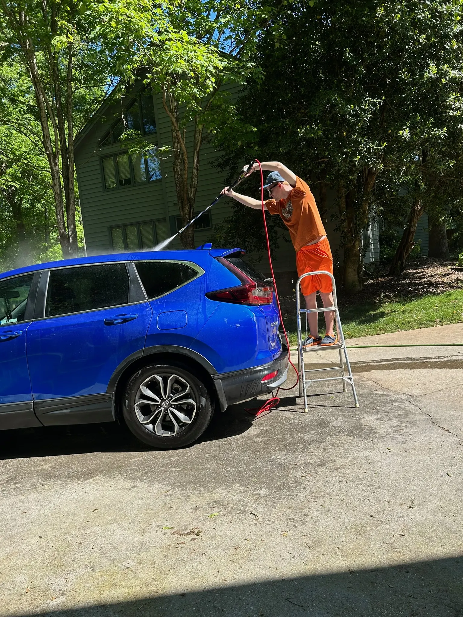 Alexander rinsing a blue SUV during a real detailing appointment