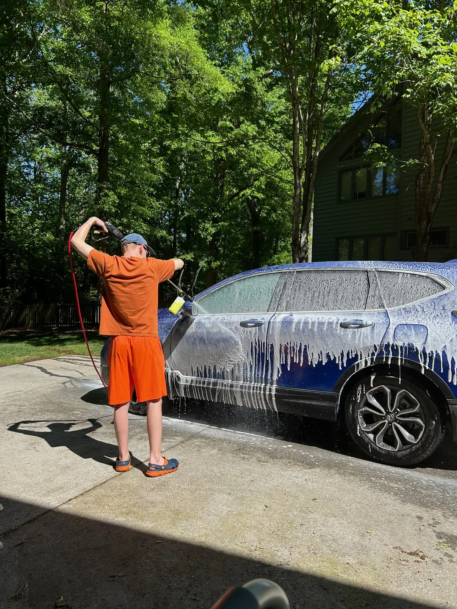 Alexander foaming a blue SUV during exterior detailing